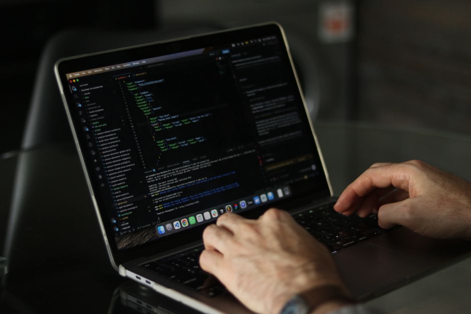 Developer's hands typing code on a laptop while cutting GitHub Copilot token usage