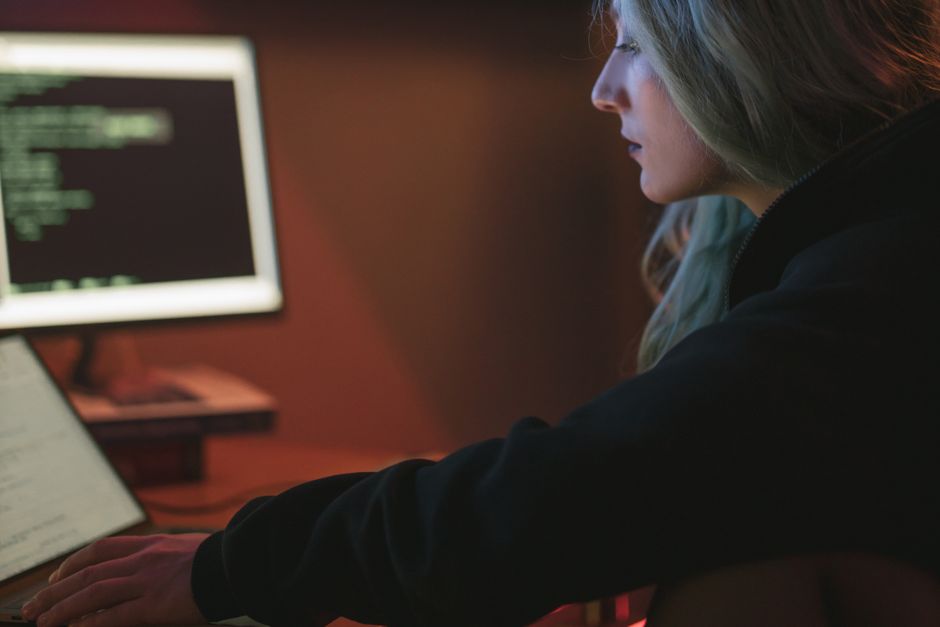 Developer working late on a laptop with code displayed on the screen in a dark room, representing a Warp Agent Mode session